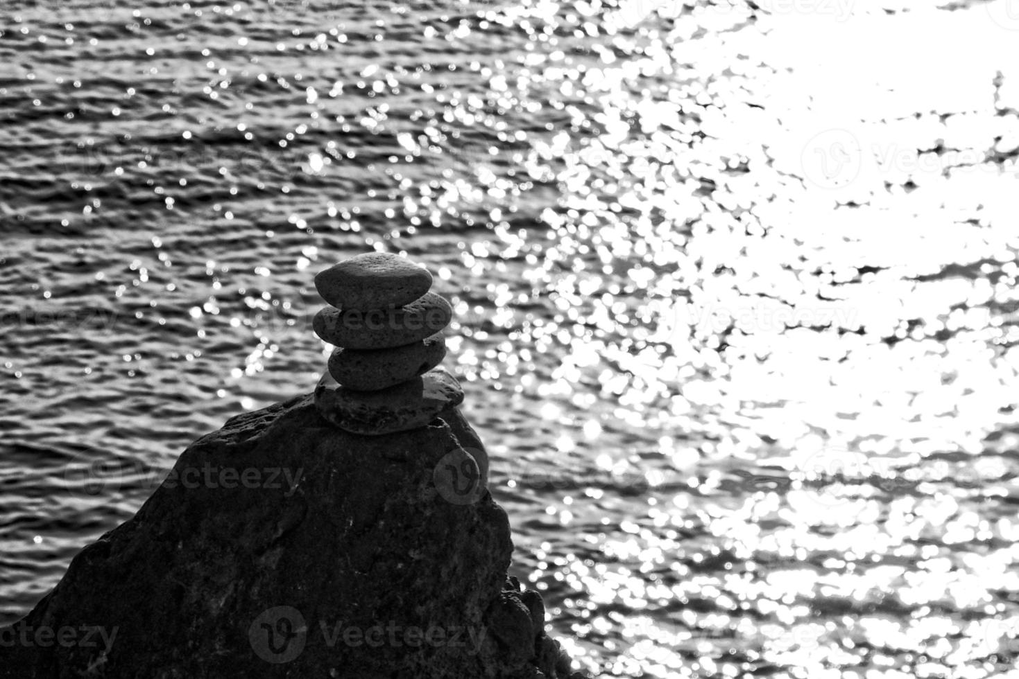 calm view of the ocean with sun reflections and a pile of stones photo