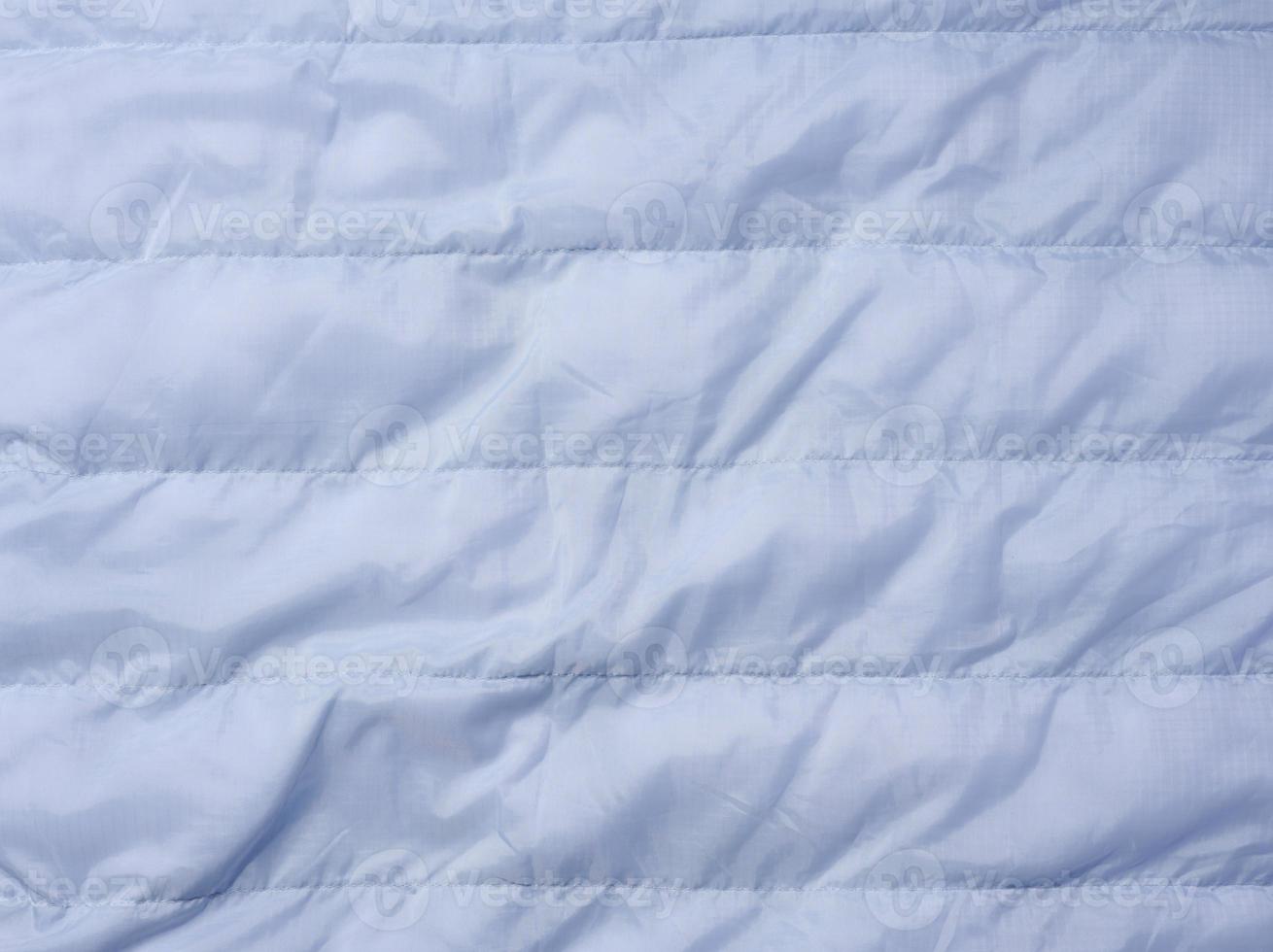 A fragment of blue fabric with down filling and stitching, fabric for jackets and coats photo