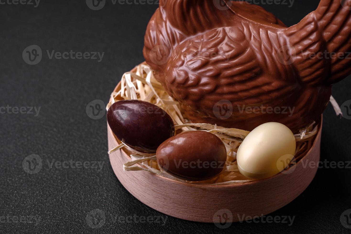 Chocolate Easter hen and eggs in a nest with straw photo