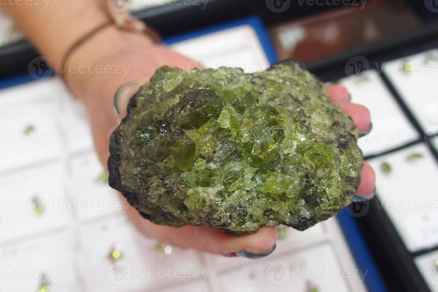 large lump of olivine precious stone held in the hand in close-up photo
