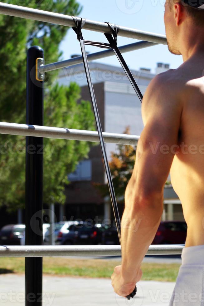 Athletic man workout with expander in the street, outdoor training photo