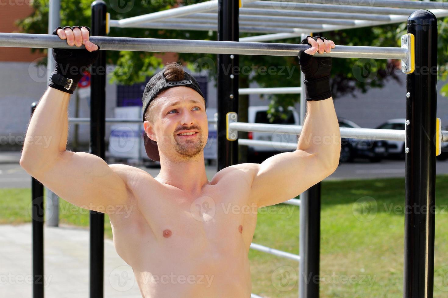 Man doing workout on horizontal bar on the street photo