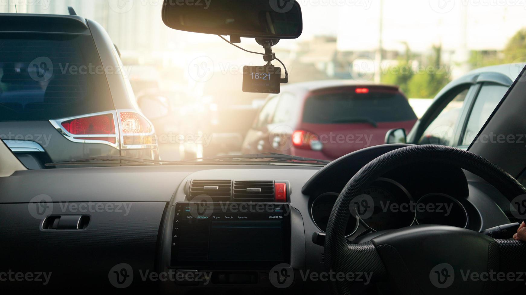 Transportation driving inside car. Console car with LCD monitor. On top with camera recoder. Saw a small hand on the steering wheel of the car. background traffic jam of cars in evening time. photo