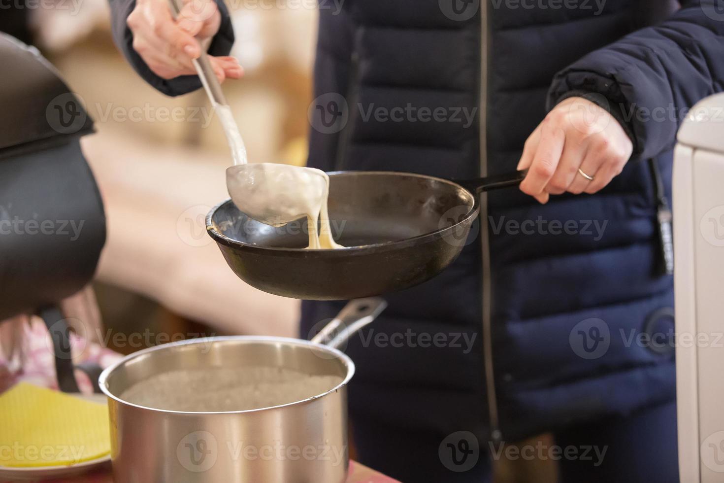 Pancakes are cooked on the street. Pour pancake dough into a pan. Maslenitsa. photo