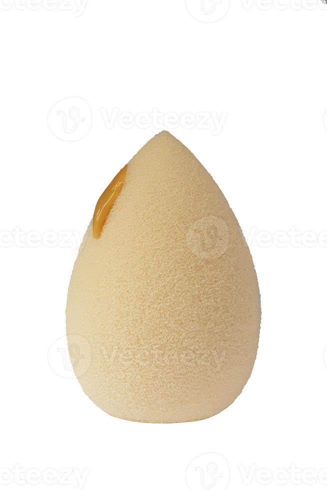 Cosmetic face sponge with a drop of foundation cream isolated on a white background. photo