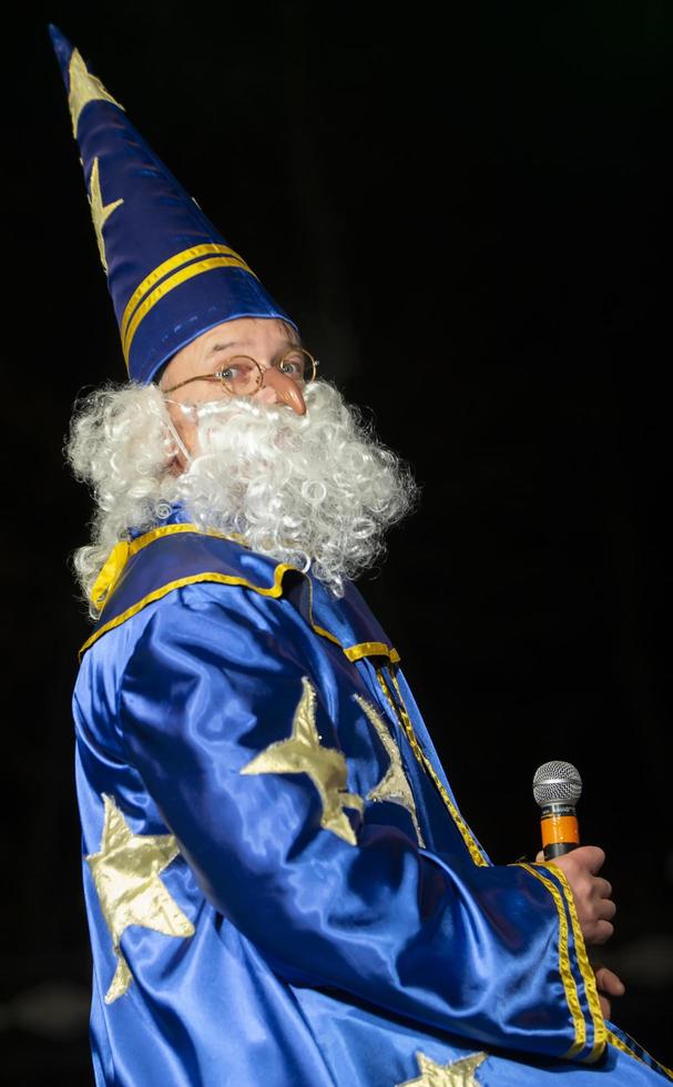 bielorrusia, el ciudad de gomil, diciembre 10, 2019. el fiesta de Encendiendo el Navidad arbol.a hombre en un mago disfraz con un micrófono. astrólogo. foto