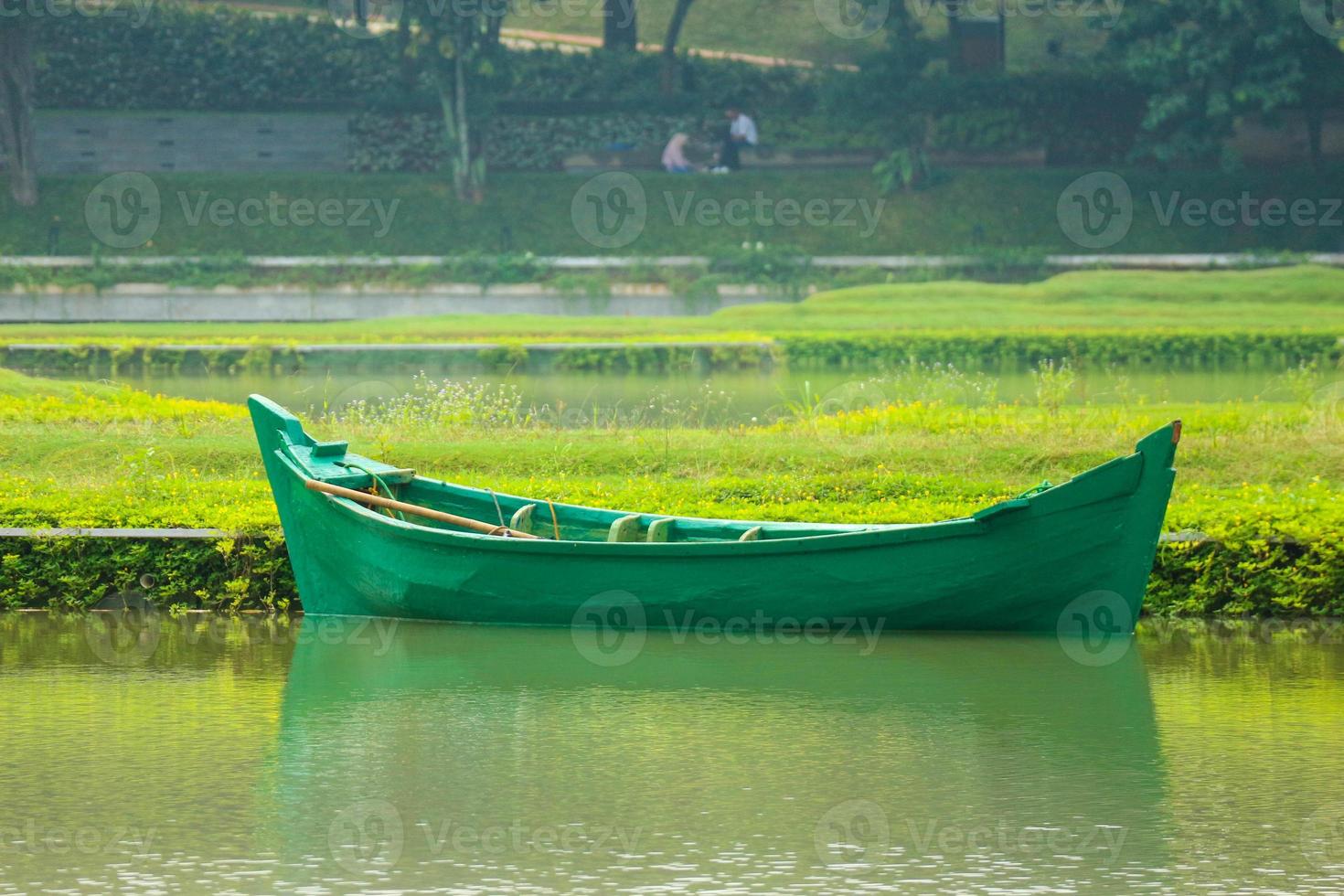 A green boat without passengers was parked on the edge of the lake. photo