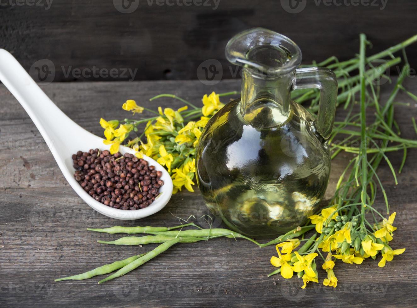 canola oil, flowers and seeds on rustic wood photo