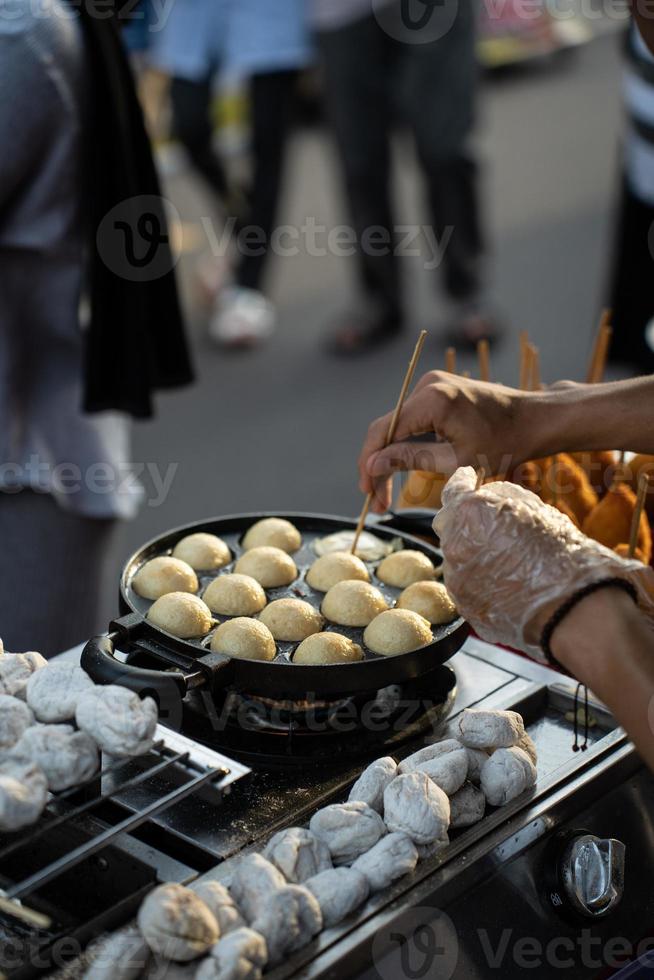 comida vendedores haciendo takoyaki, un delicioso calle comida bocadillo a el jogokariyan ramadhan mercado foto