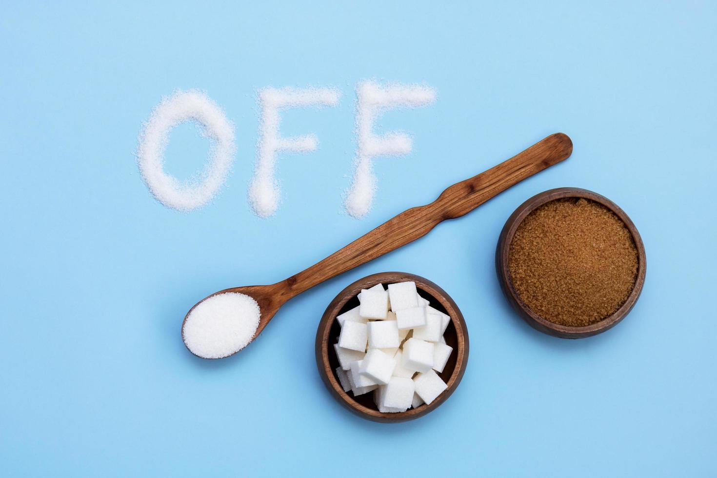 inscription off next to different types of sugar in wooden cups and spoon photo