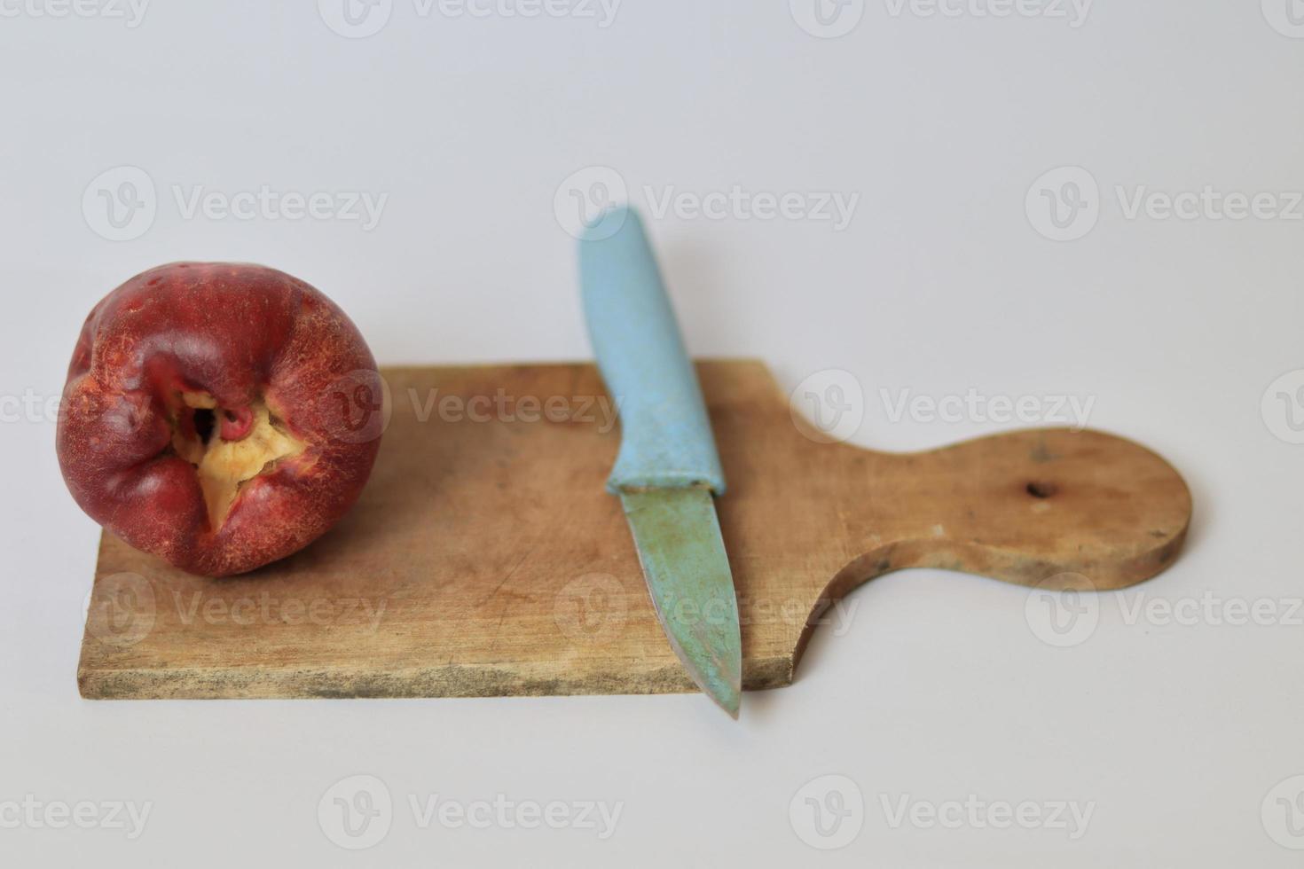 rojo jambu bol o Jamaica guayaba siguiente a un azul cuchillo en un corte tablero en contra un blanco antecedentes foto