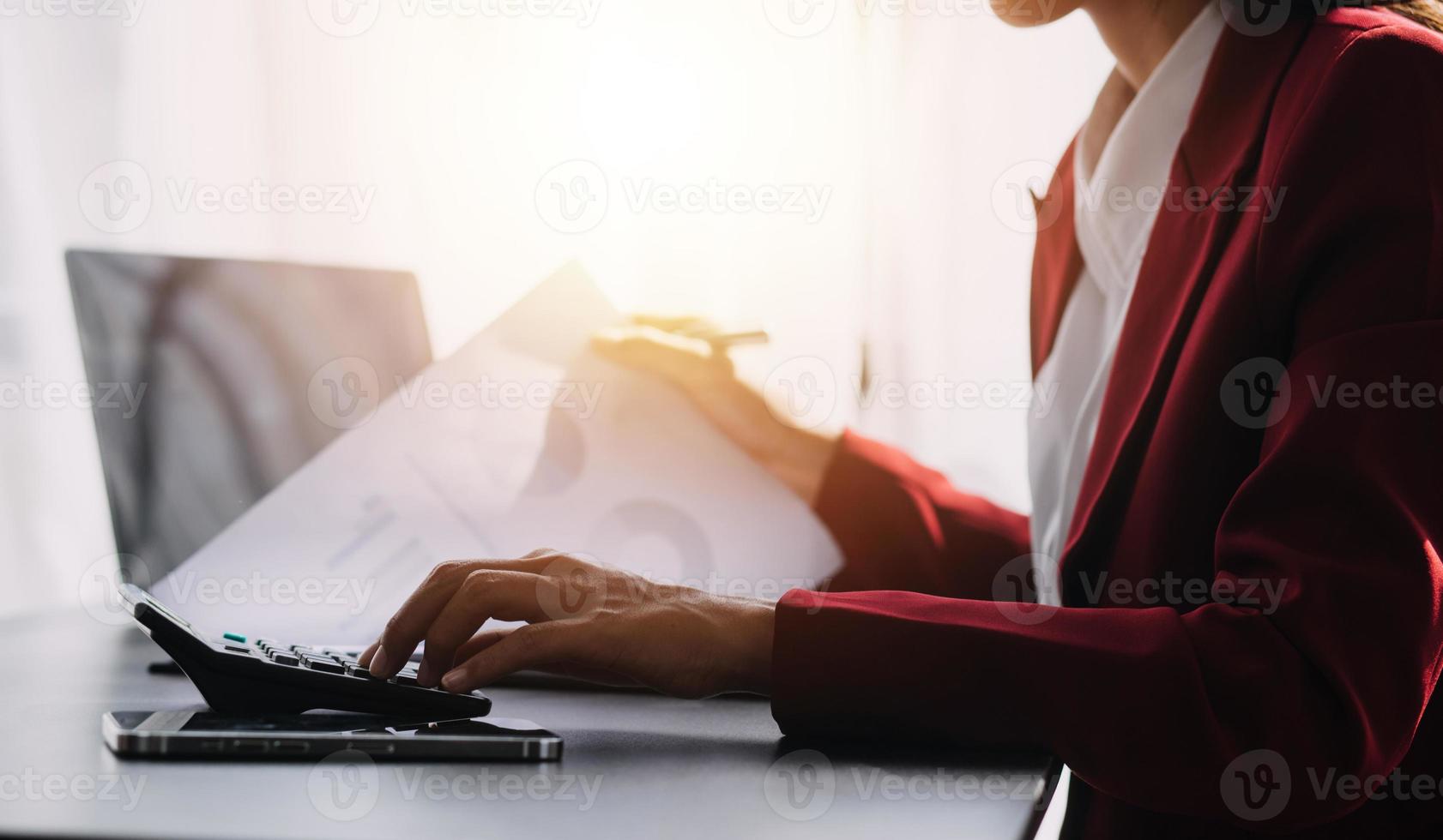 Asian Business woman using calculator and laptop for doing math finance on an office desk, tax, report, accounting, statistics, and analytical research concept photo