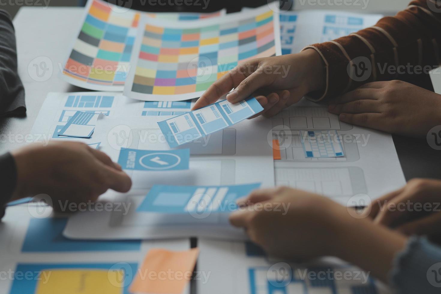 Close up ux developer and ui designer brainstorming about mobile app interface wireframe design on table with customer breif and color code at modern office.Creative digital development agency photo