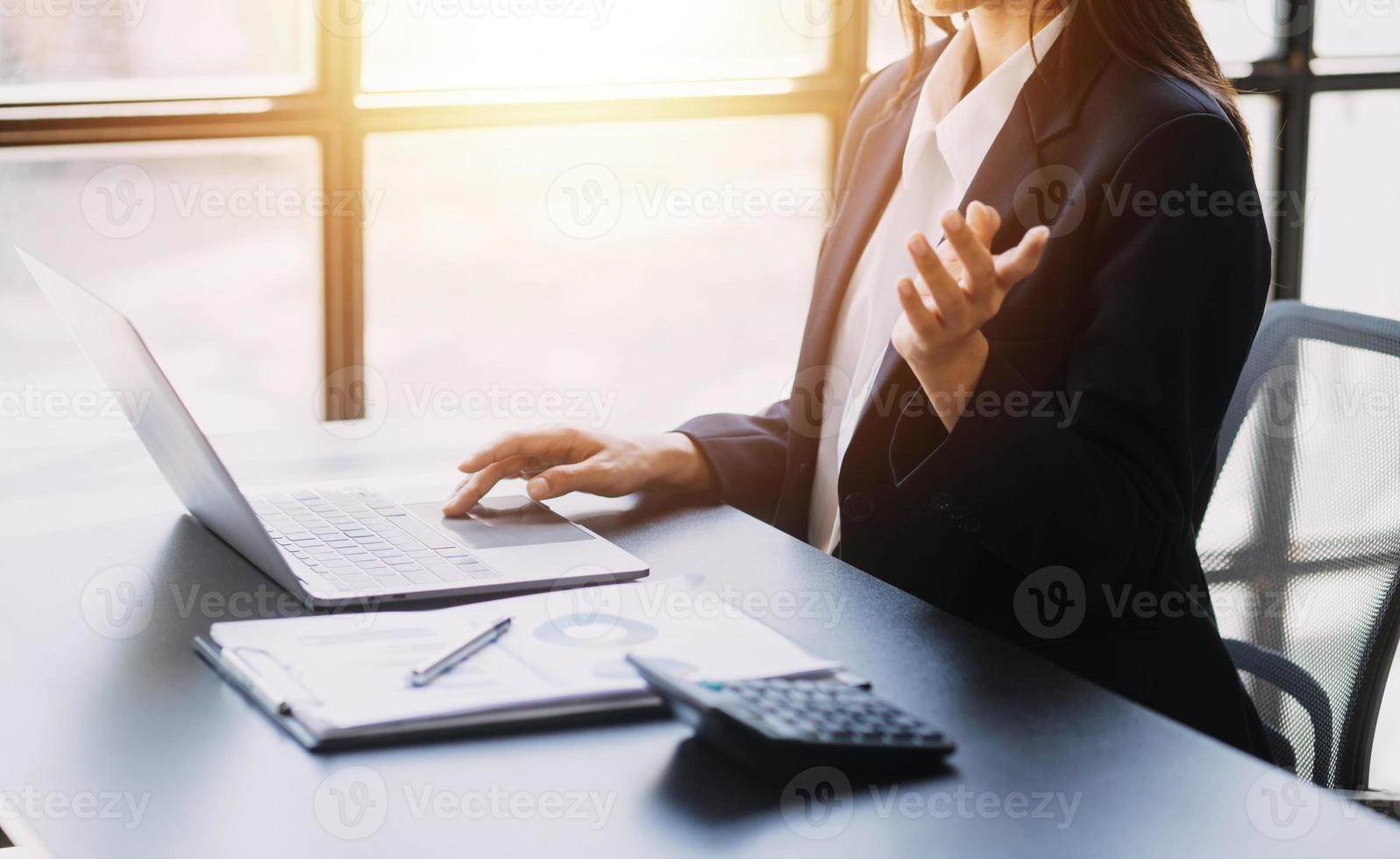 Asian Business woman using calculator and laptop for doing math finance on an office desk, tax, report, accounting, statistics, and analytical research concept photo