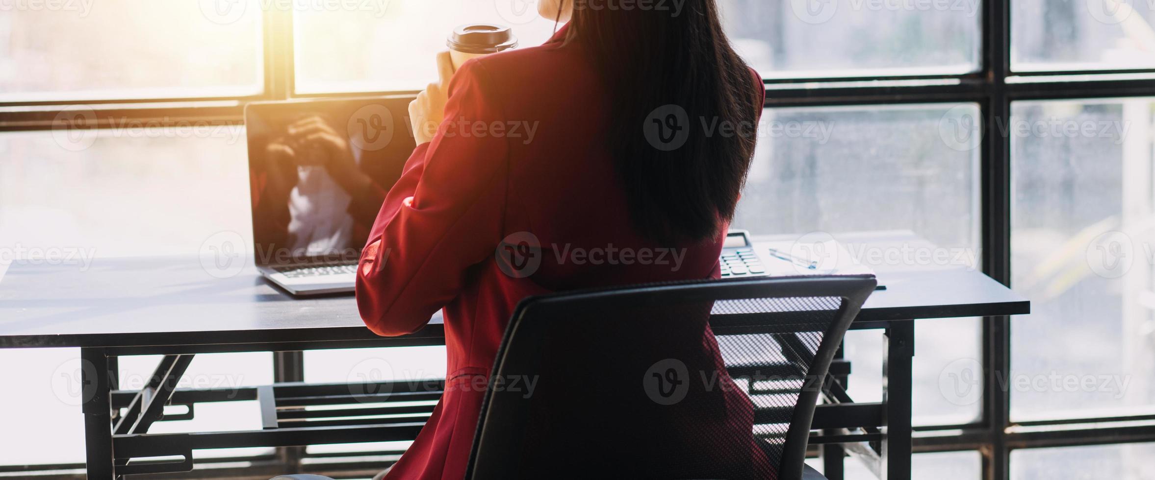 Asian Business woman using calculator and laptop for doing math finance on an office desk, tax, report, accounting, statistics, and analytical research concept photo