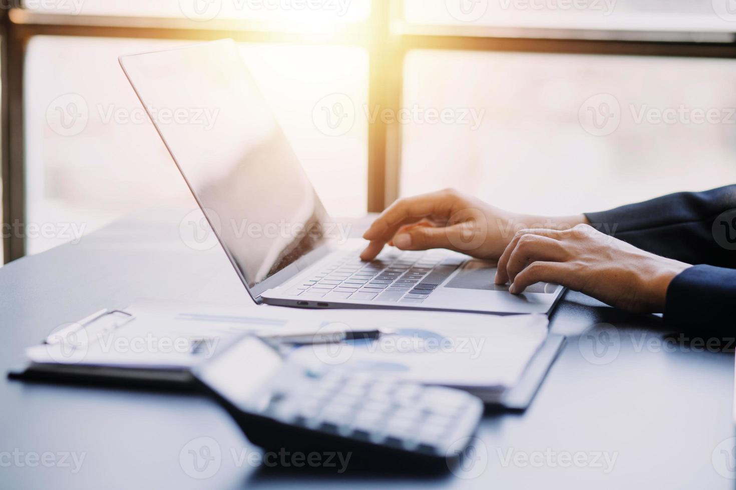Asian Business woman using calculator and laptop for doing math finance on an office desk, tax, report, accounting, statistics, and analytical research concept photo