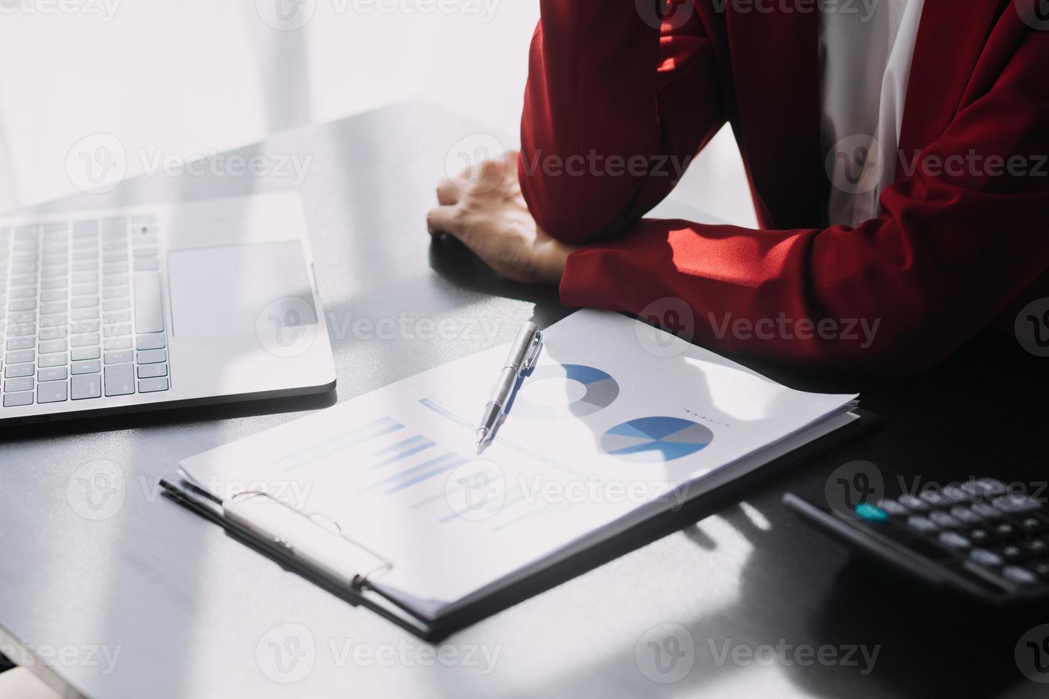 Asian Business woman using calculator and laptop for doing math finance on an office desk, tax, report, accounting, statistics, and analytical research concept photo