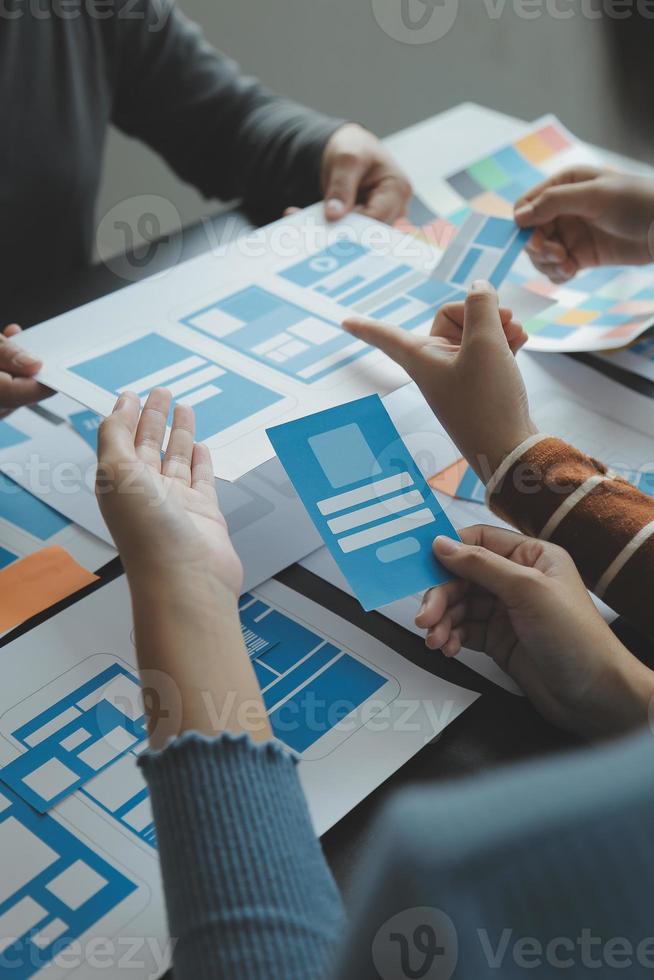 Close up ux developer and ui designer brainstorming about mobile app interface wireframe design on table with customer breif and color code at modern office.Creative digital development agency photo