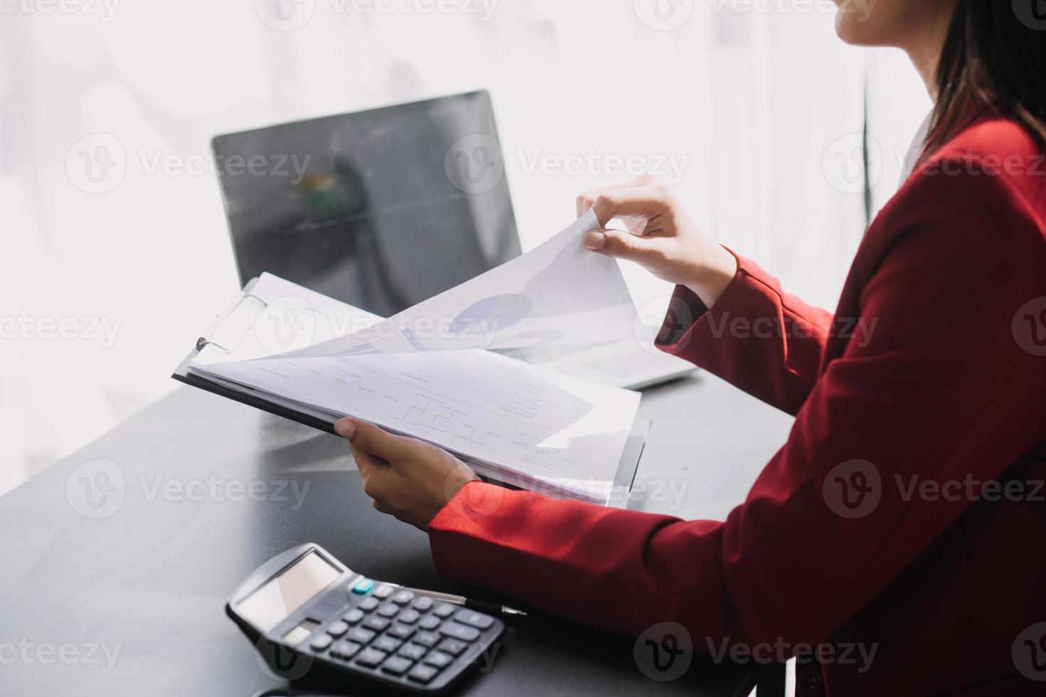 Asian Business woman using calculator and laptop for doing math finance on an office desk, tax, report, accounting, statistics, and analytical research concept photo