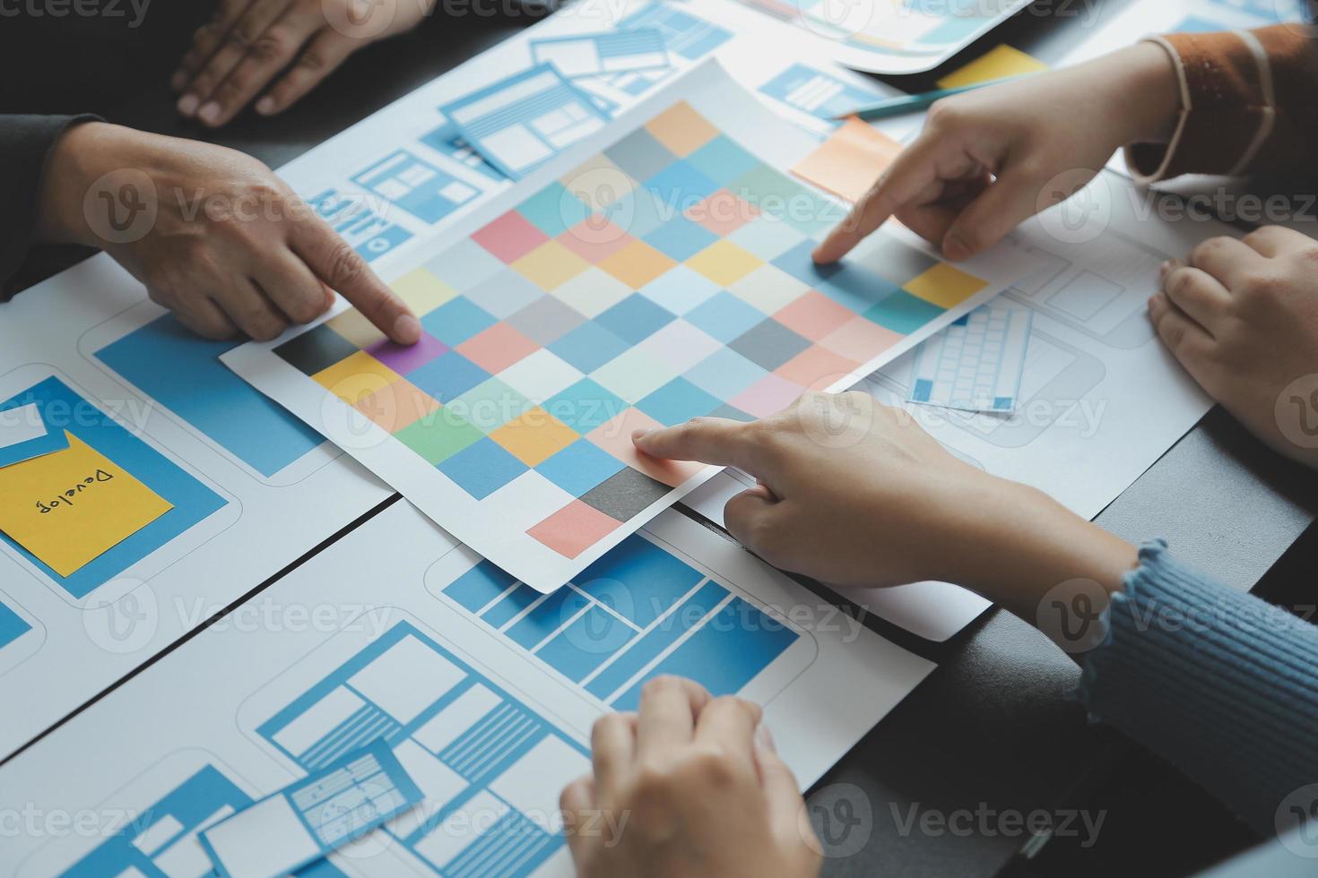 Close up ux developer and ui designer brainstorming about mobile app interface wireframe design on table with customer breif and color code at modern office.Creative digital development agency photo