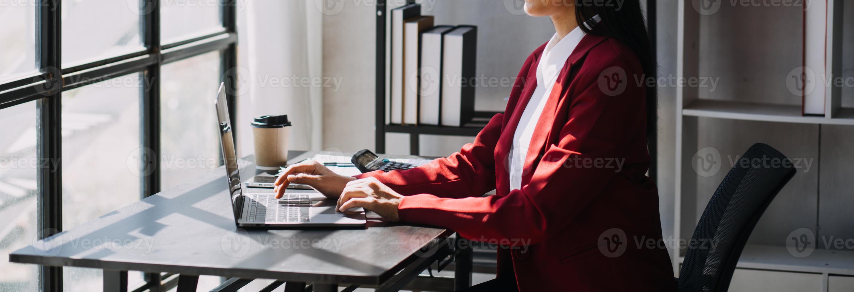 Asian Business woman using calculator and laptop for doing math finance on an office desk, tax, report, accounting, statistics, and analytical research concept photo