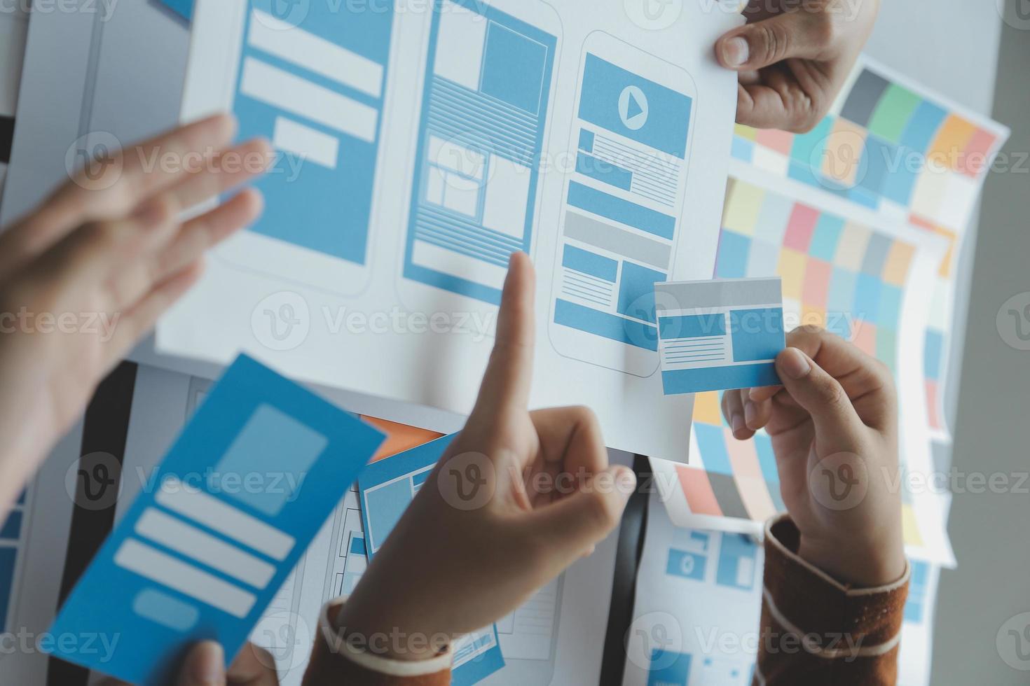 Close up ux developer and ui designer brainstorming about mobile app interface wireframe design on table with customer breif and color code at modern office.Creative digital development agency photo
