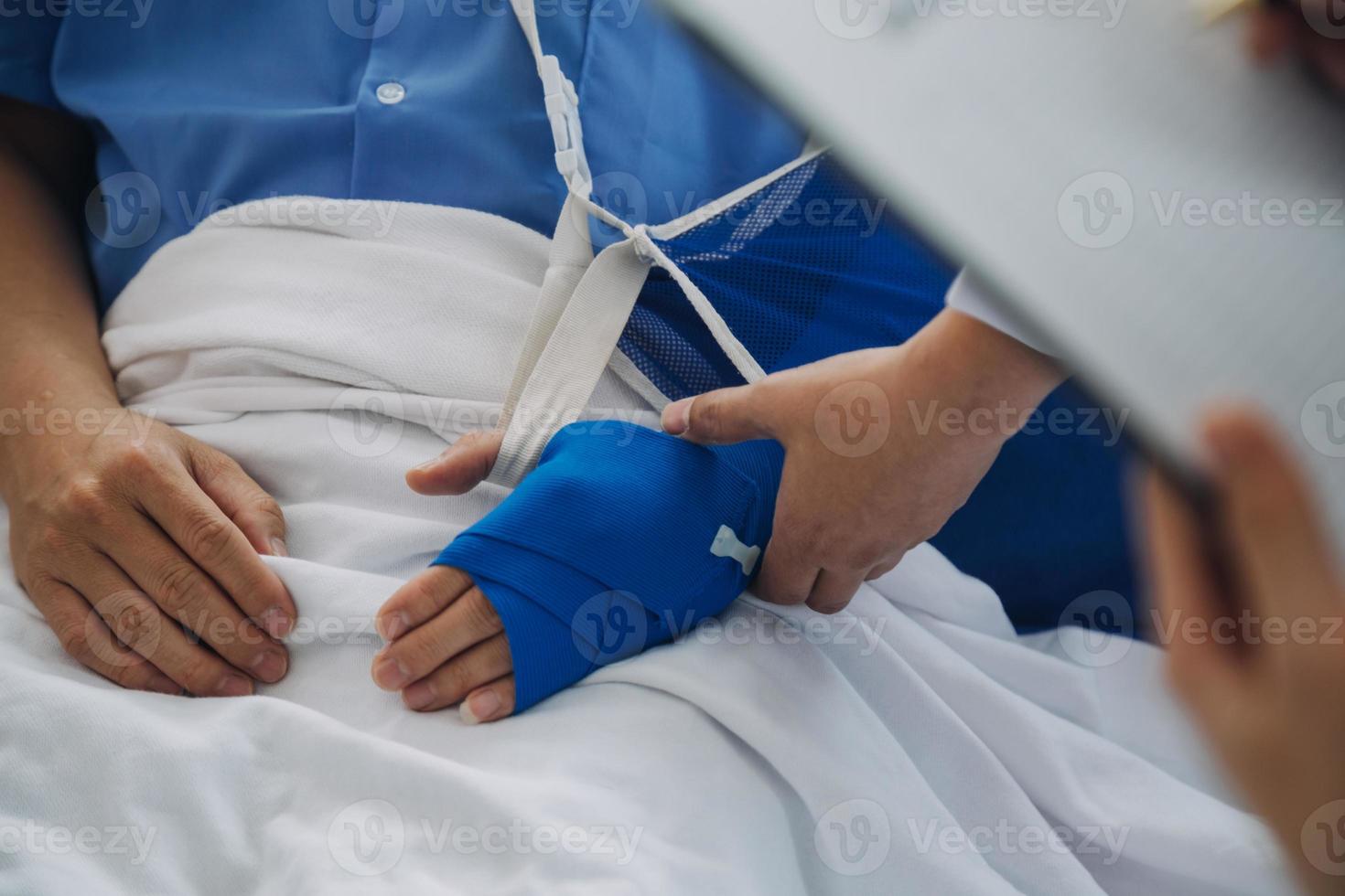 Man with broken arm in cast lying on bed in hospital. The emergency center treatment is plaster and hangs with sling for a further cure in an orthopedic clinic. Patient pain from accident injury. photo