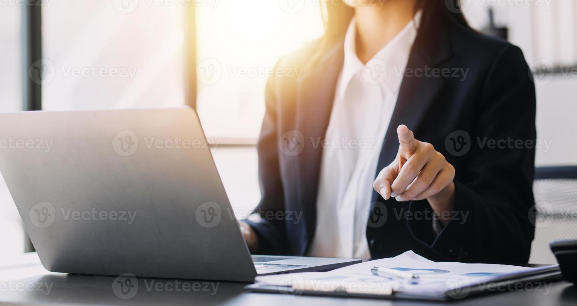 Asian Business woman using calculator and laptop for doing math finance on an office desk, tax, report, accounting, statistics, and analytical research concept photo
