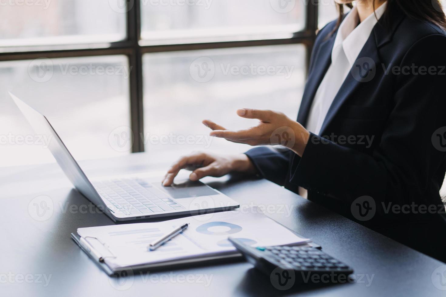 Asian Business woman using calculator and laptop for doing math finance on an office desk, tax, report, accounting, statistics, and analytical research concept photo