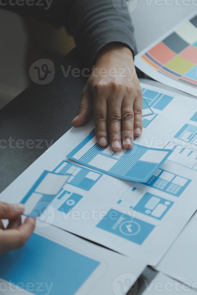 Close up ux developer and ui designer brainstorming about mobile app interface wireframe design on table with customer breif and color code at modern office.Creative digital development agency photo