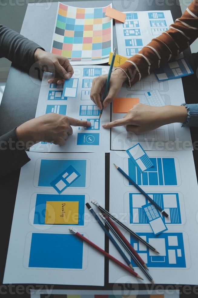 Close up ux developer and ui designer brainstorming about mobile app interface wireframe design on table with customer breif and color code at modern office.Creative digital development agency photo