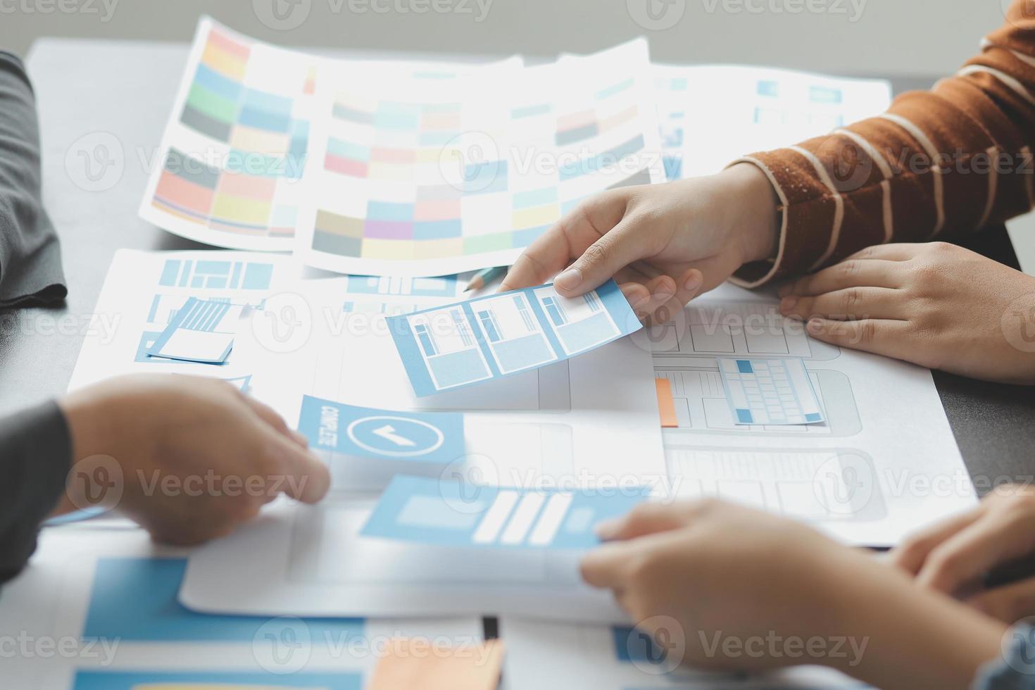 Close up ux developer and ui designer brainstorming about mobile app interface wireframe design on table with customer breif and color code at modern office.Creative digital development agency photo