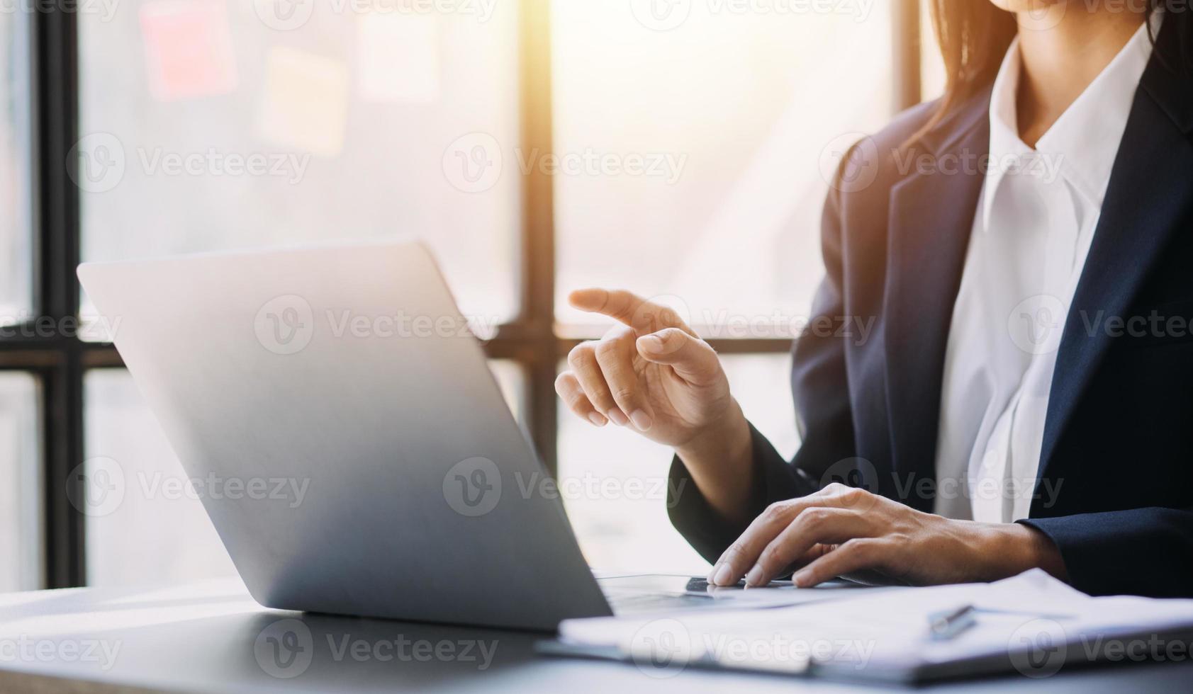 Asian Business woman using calculator and laptop for doing math finance on an office desk, tax, report, accounting, statistics, and analytical research concept photo