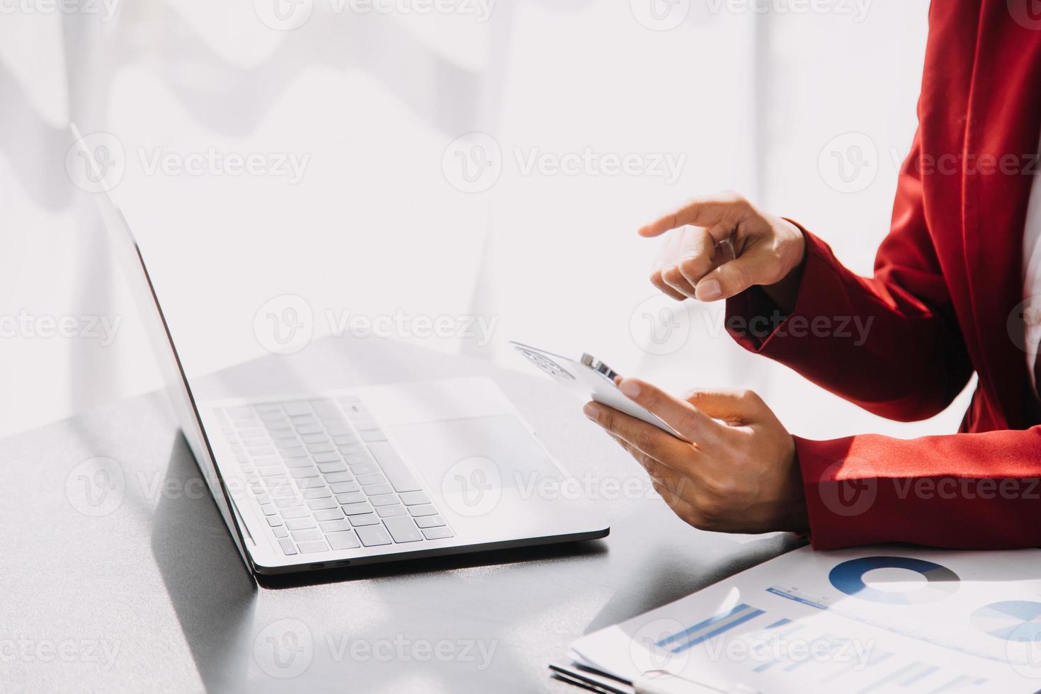 Asian Business woman using calculator and laptop for doing math finance on an office desk, tax, report, accounting, statistics, and analytical research concept photo