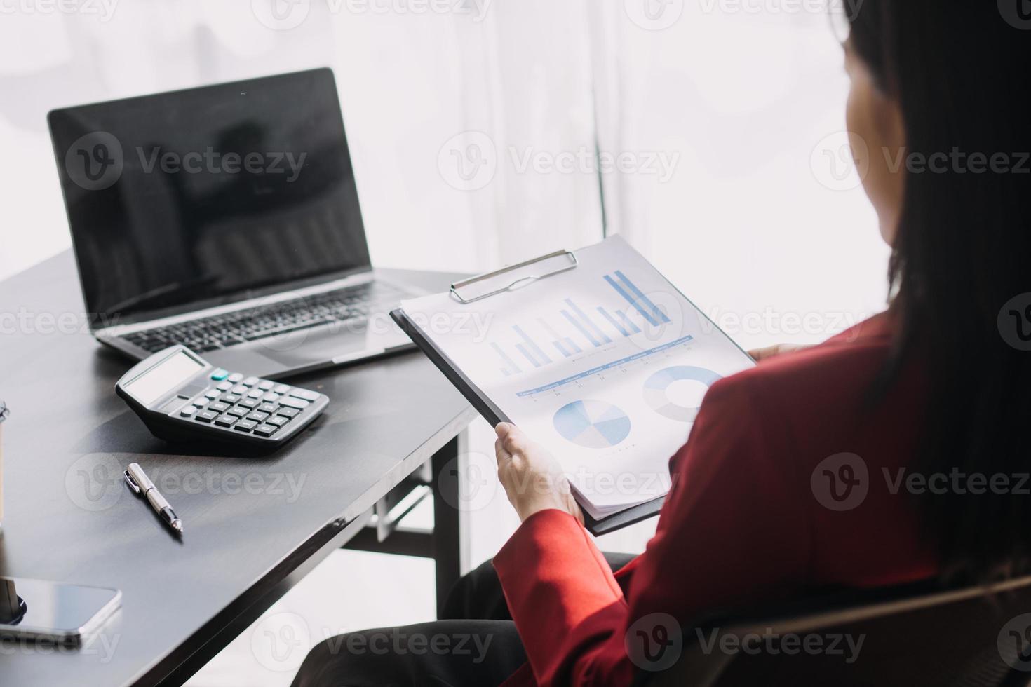 Asian Business woman using calculator and laptop for doing math finance on an office desk, tax, report, accounting, statistics, and analytical research concept photo