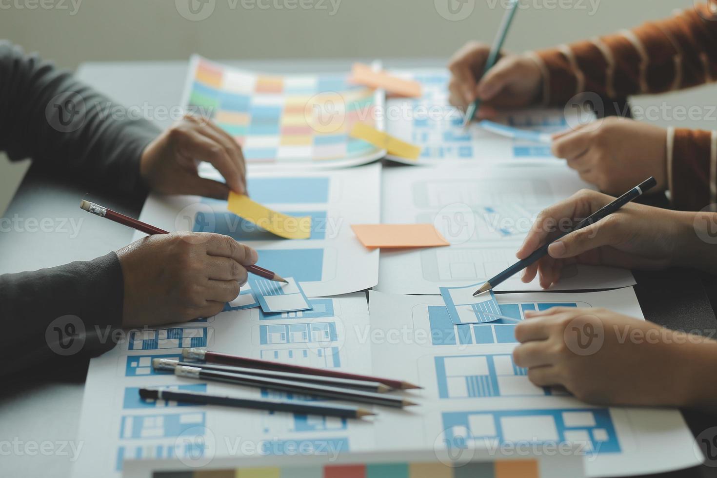 Close up ux developer and ui designer brainstorming about mobile app interface wireframe design on table with customer breif and color code at modern office.Creative digital development agency photo