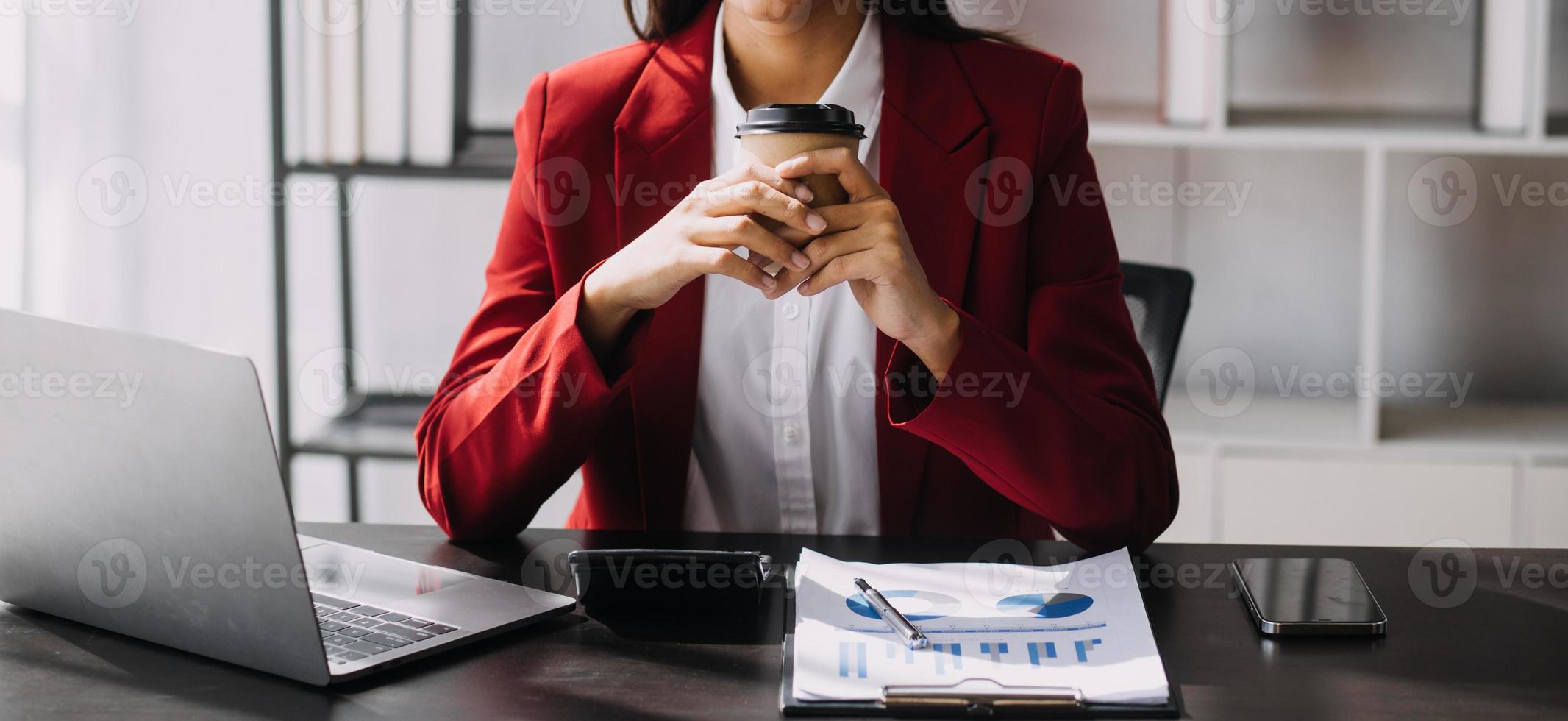 Asian Business woman using calculator and laptop for doing math finance on an office desk, tax, report, accounting, statistics, and analytical research concept photo