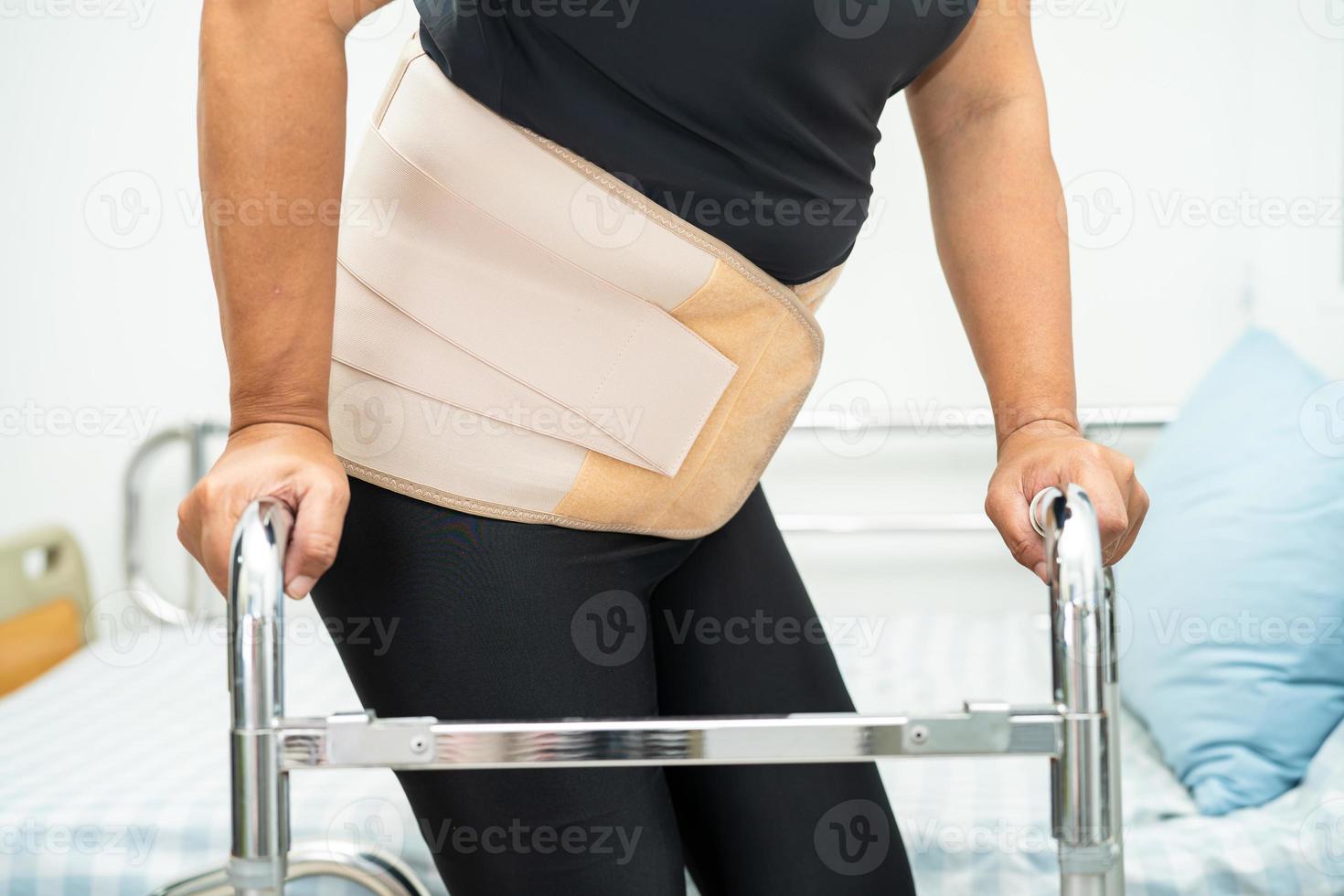 Asian lady patient wearing back pain support belt for orthopedic lumbar with walker. photo