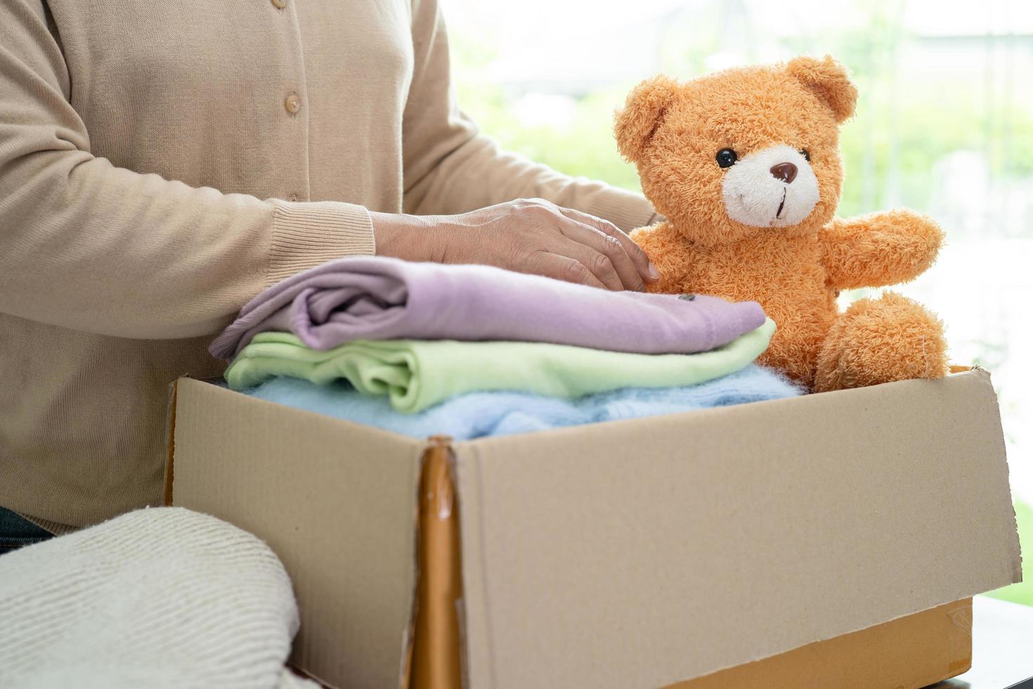 Donation box with used clothes and doll at home to support help for poor people in the world. photo