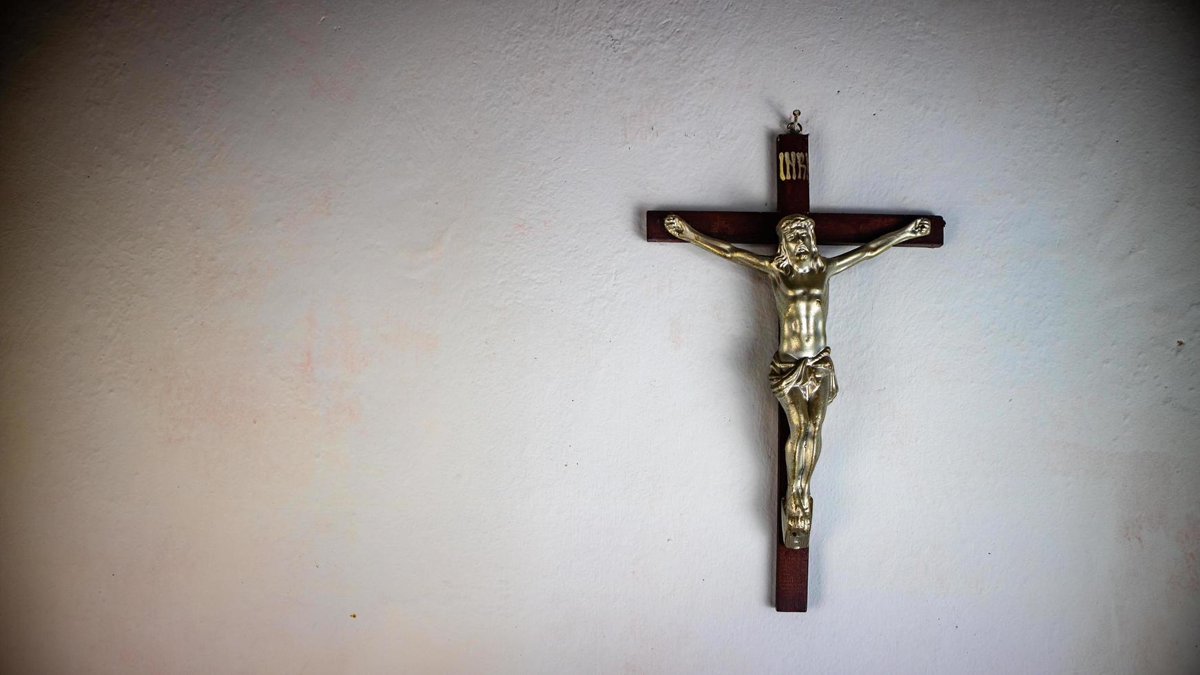 a cross hung on a white wall photo