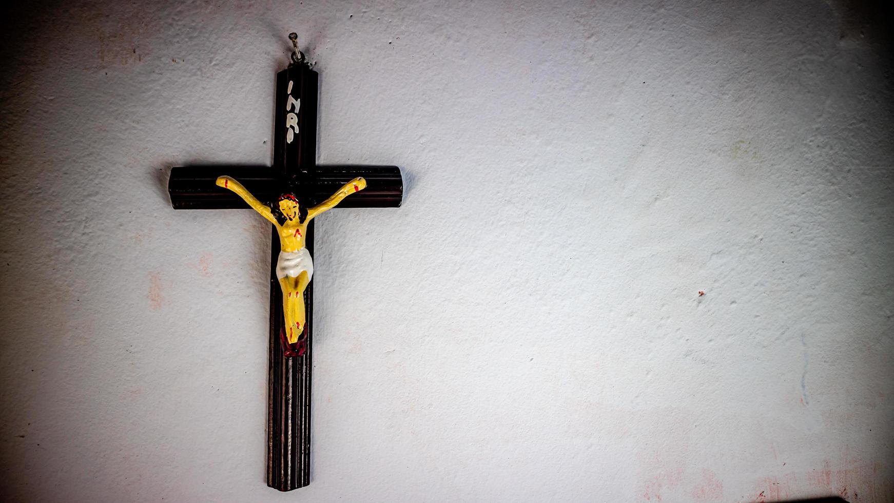 a cross hung on a white wall photo