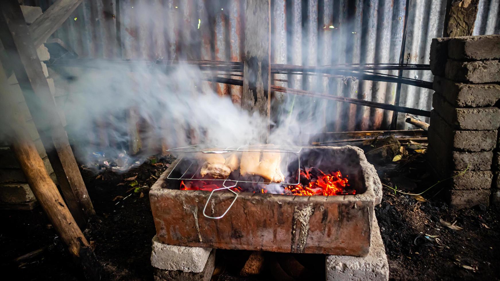 Cerdo siendo A la parrilla en carbones foto