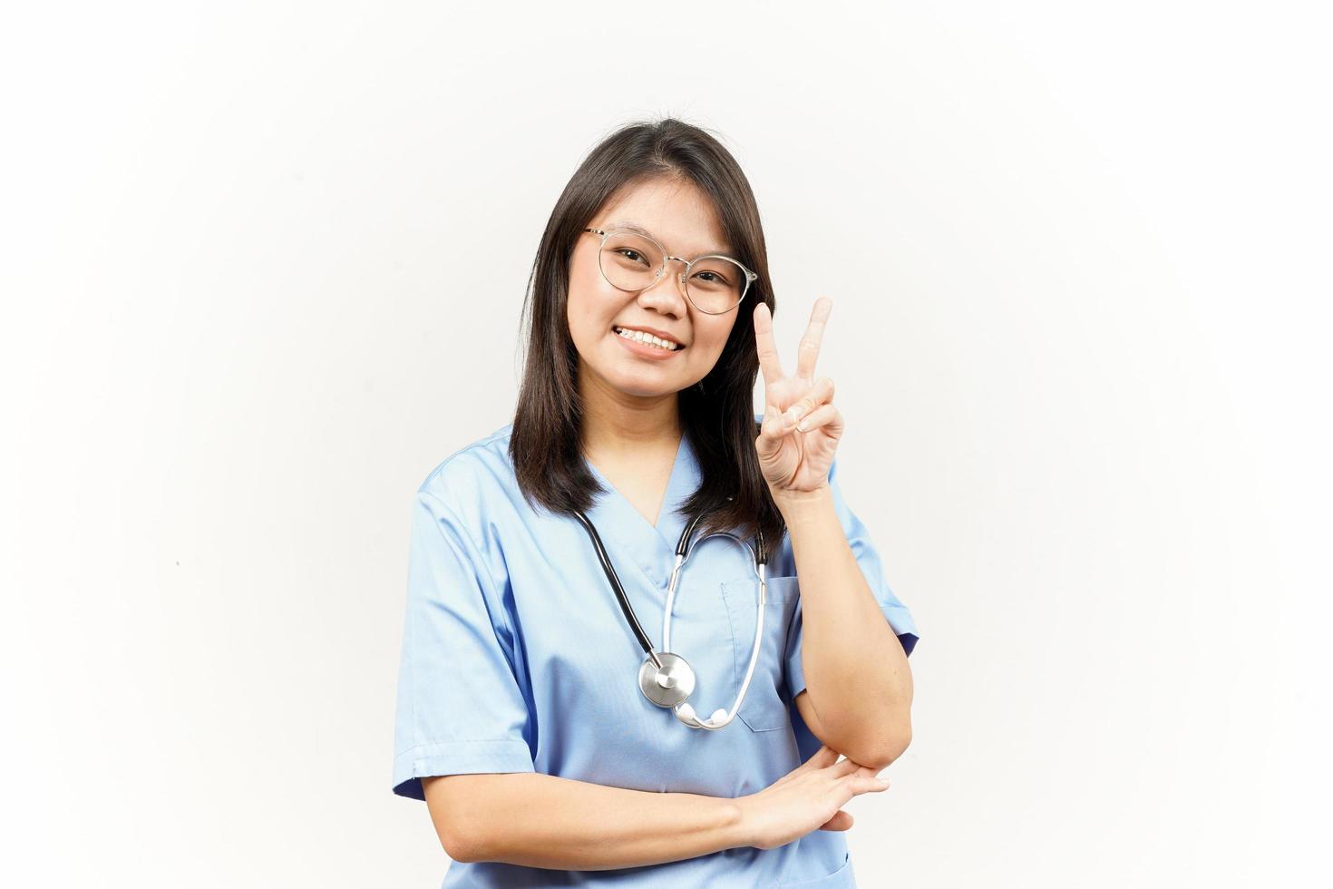 Showing Peace Sign Of Asian Young Doctor Isolated On White Background photo