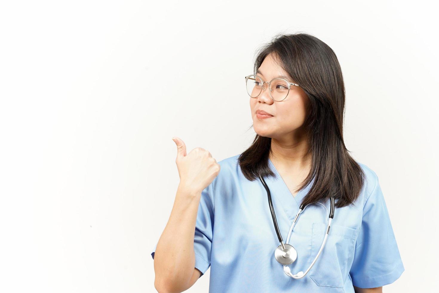 demostración y señalando producto con pulgar de asiático joven médico aislado en blanco antecedentes foto