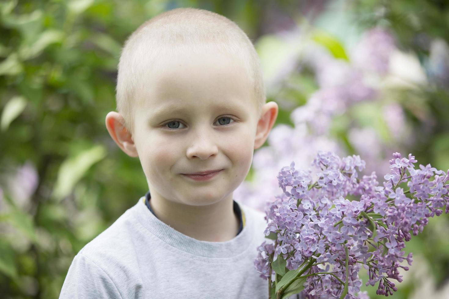 A child in a lilac. Laughing boy with a bouquet of spring flowers. photo
