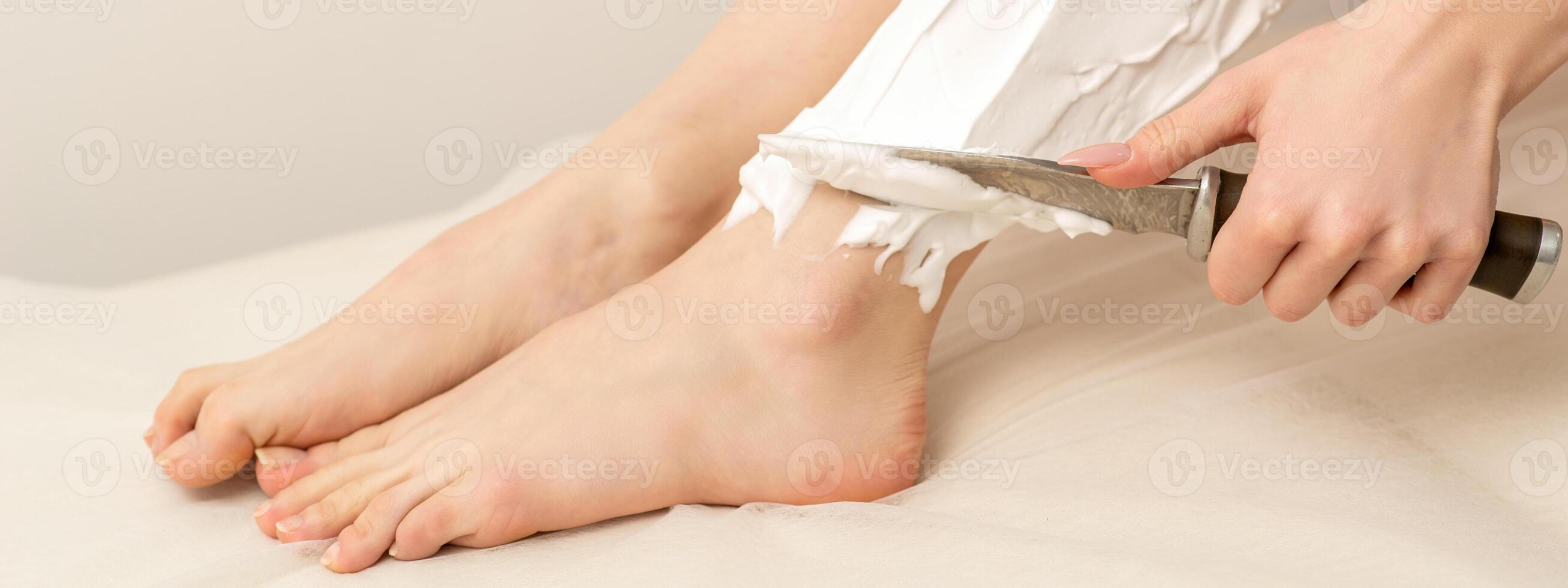 Woman shaving legs with knife photo