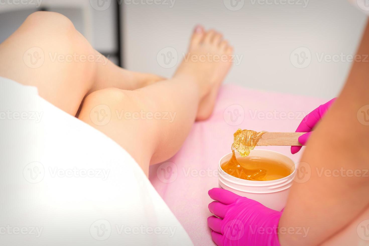 Cosmetologists waxing the female legs photo