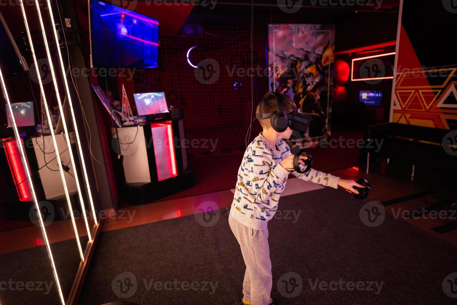 Boy kid playing game using virtual reality headset and gamepads in playing club. photo