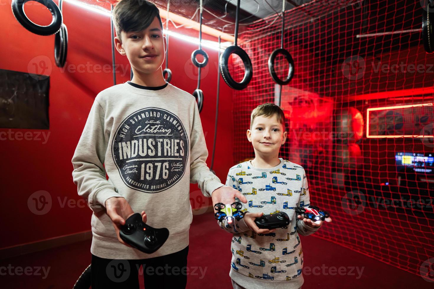 Children flying remote control drones game indoor play zone. photo