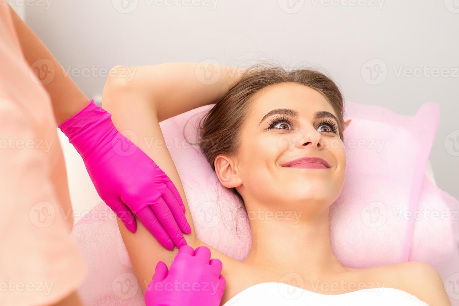 Woman receiving waxing her armpit photo